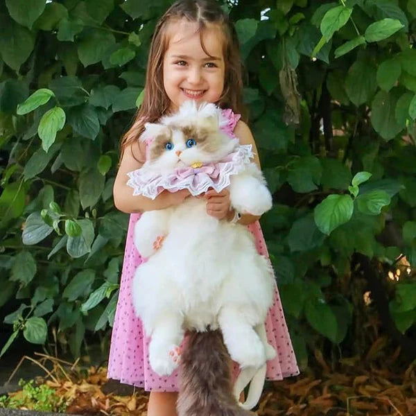 Child holding a lifelike stuffed cat plush travel backpack cute ragdoll cat bag with blue eyes in front of green foliage