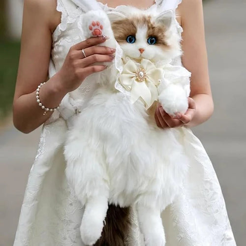 Person holding a Alvina lifelike stuffed cat plush travel backpack with decorative elements in a blurred outdoor setting