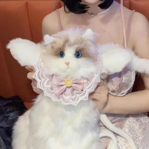 Person holding a stuffed cat plush backpack in a decorative outfit with lace and a bow.